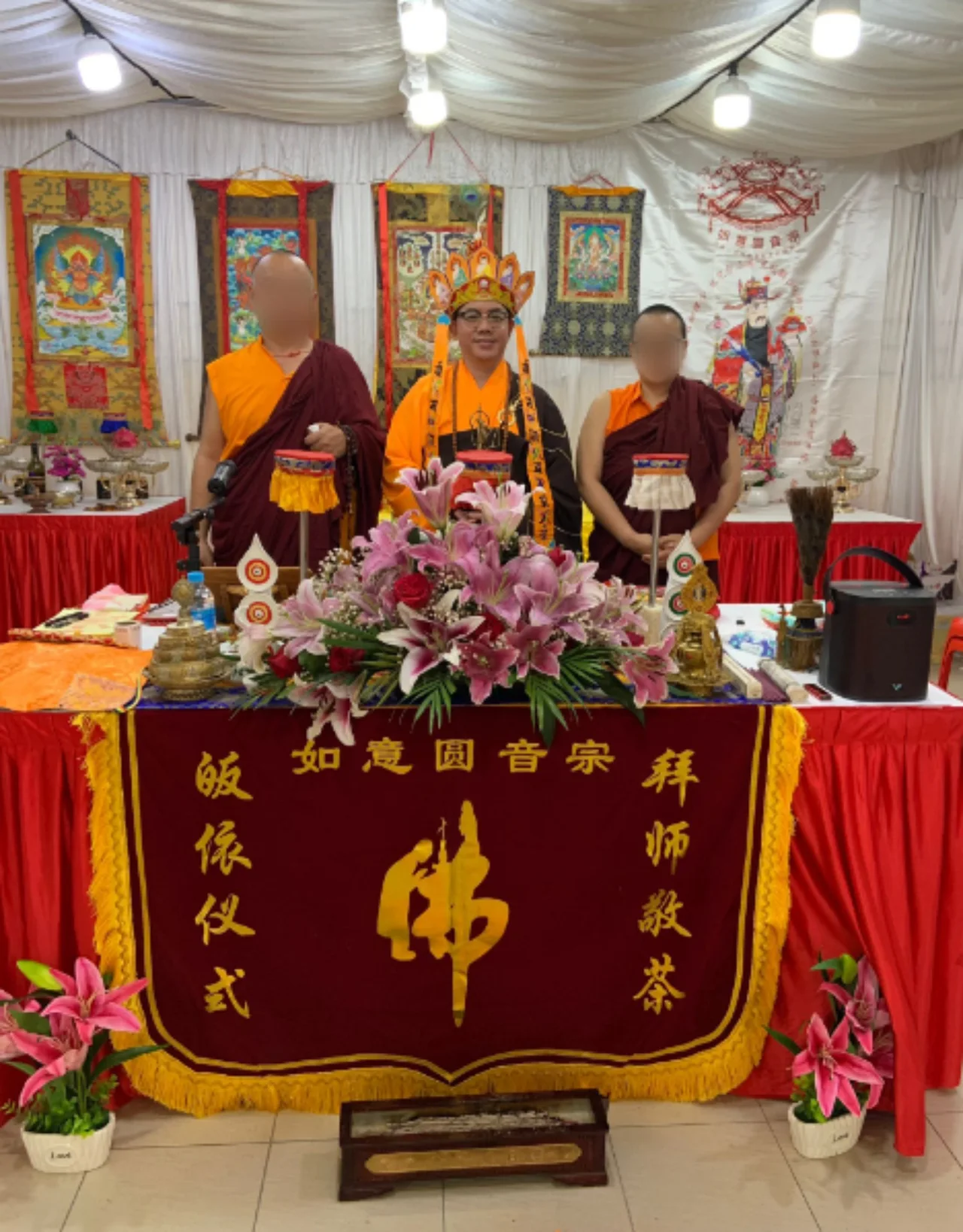 Ceremony participants behind an altar decorated with flowers and offerings.