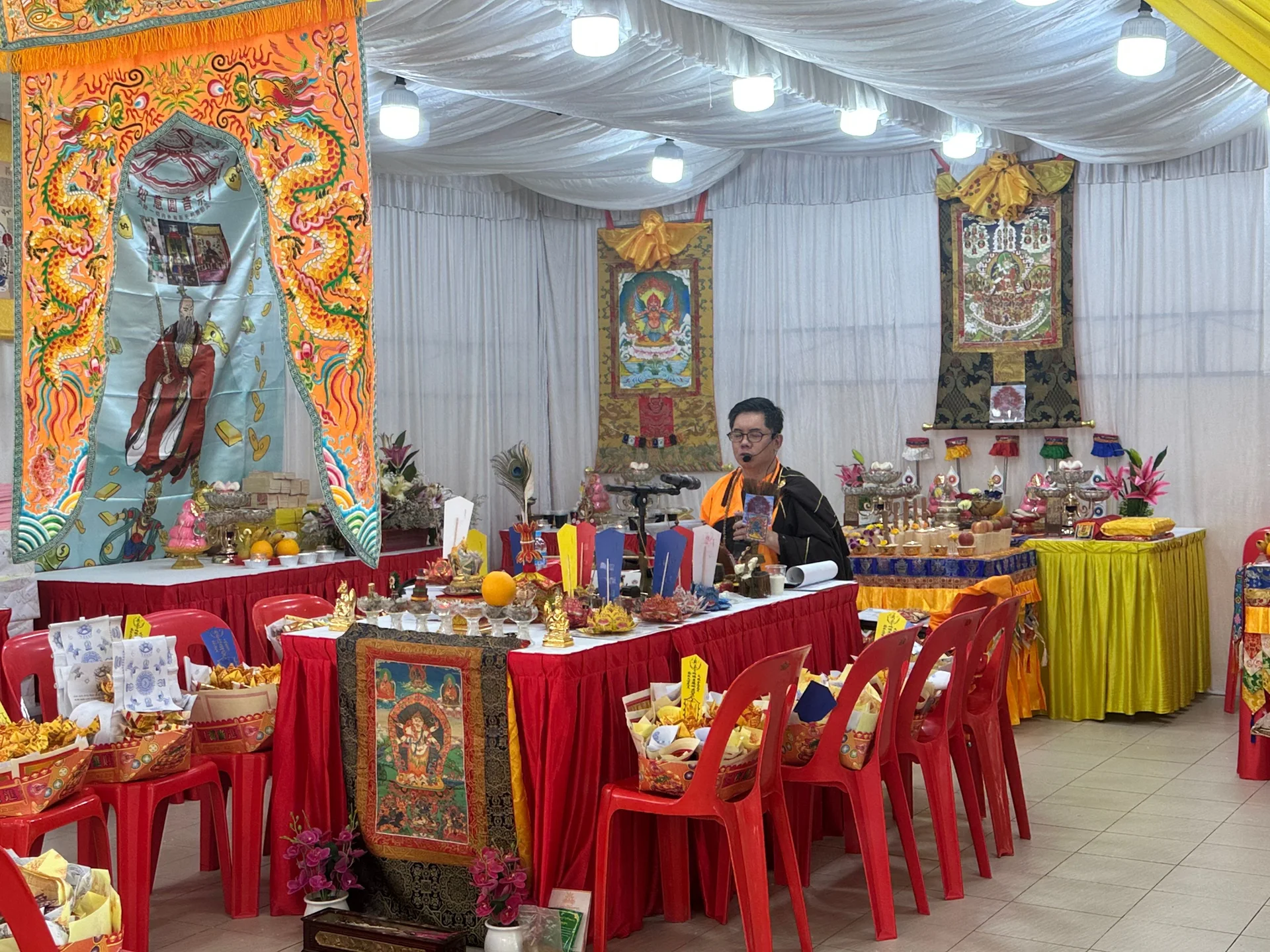 A ceremonial space with decorated altars, offerings and red chairs.